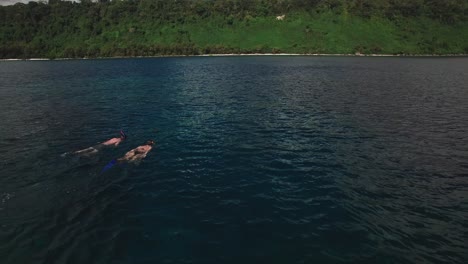Snorkeling-in-Tropical-Sea,-Aerial-View-of-Couple-in-Lagoon-Near-Exotic-Island