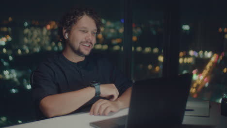 curly-haired man have online meeting late at night.