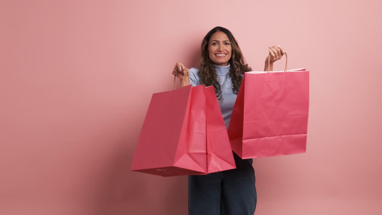 Happy hispanic woman showing pink shopping bags