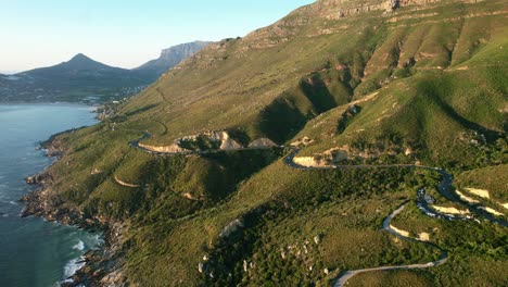 winding-mountain-roads-on-coast-of-Chapmans-Peak-in-Cape-Town-at-sunset,-aerial