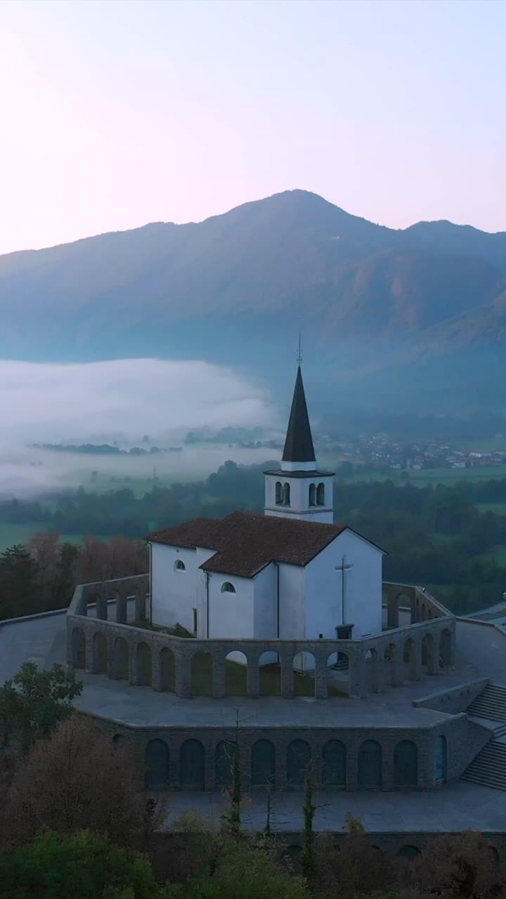 Drone in avvicinamento all'Ossario italiano di Caporetto a Kobarid, mattino di inizio primavera, buio e nebbioso, ripresa verticale