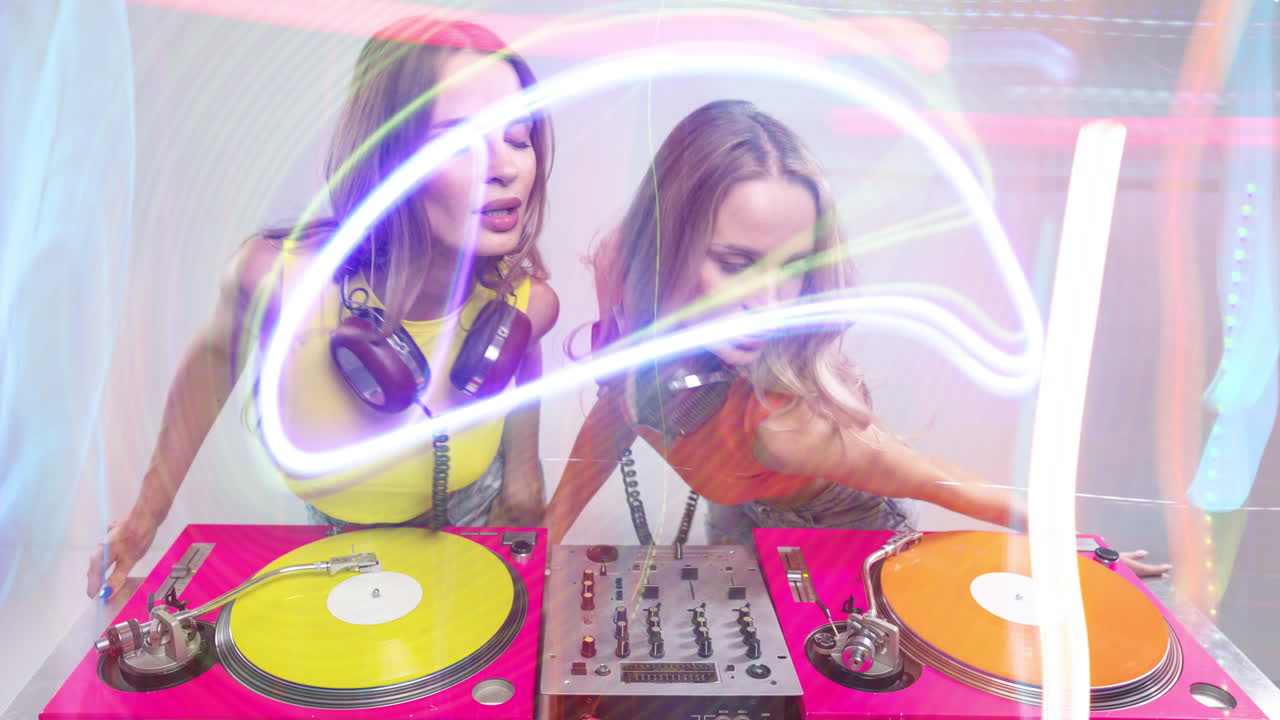 djs gemelas idénticas bailando detrás de tocadiscos y luces de discoteca