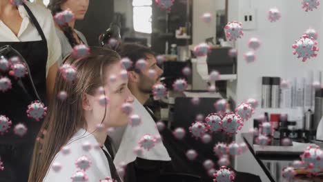 animation of macro covid-19 cells floating over caucasian man and female sitting in a hairstyle salo