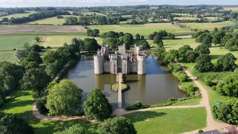incredible aerial drone footage of bodiam castle as the camera flies away from the front of castle, offering a dramatic, sweeping view. ideal for cinematic, historical, and travel content.