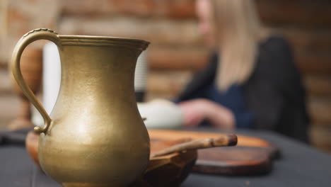 clay jug and plate with spoon on table near wooden house