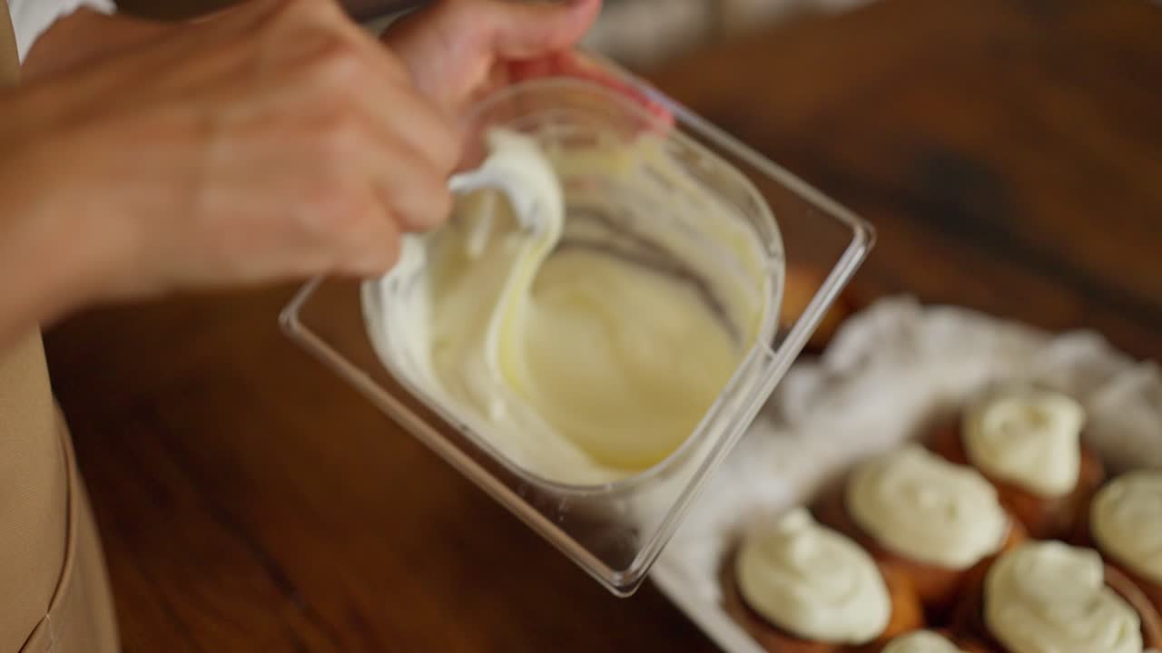 mujer frosting cupcakes con frosting blanco