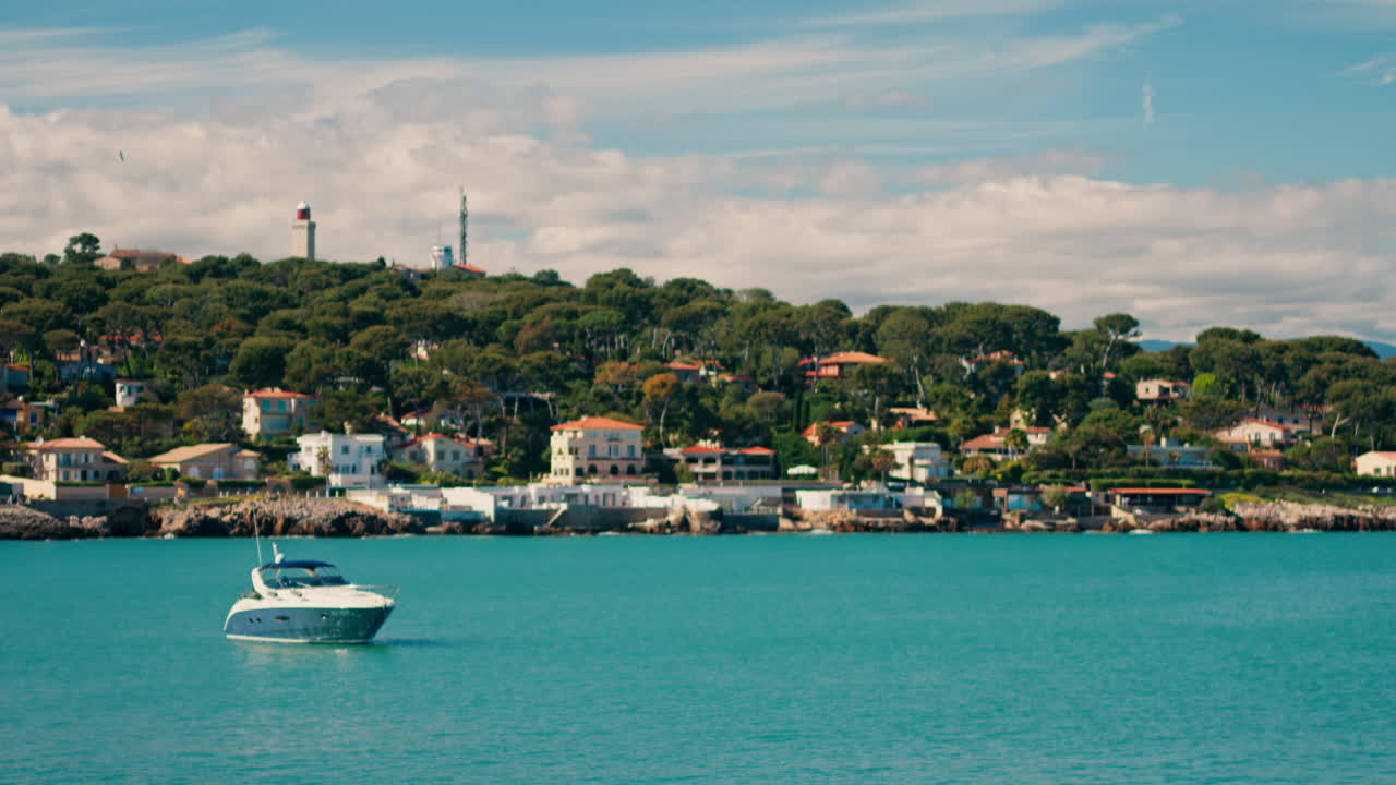 Close up of green bushes with a view of boats floating on the sea with the town of Bandol, France on the background