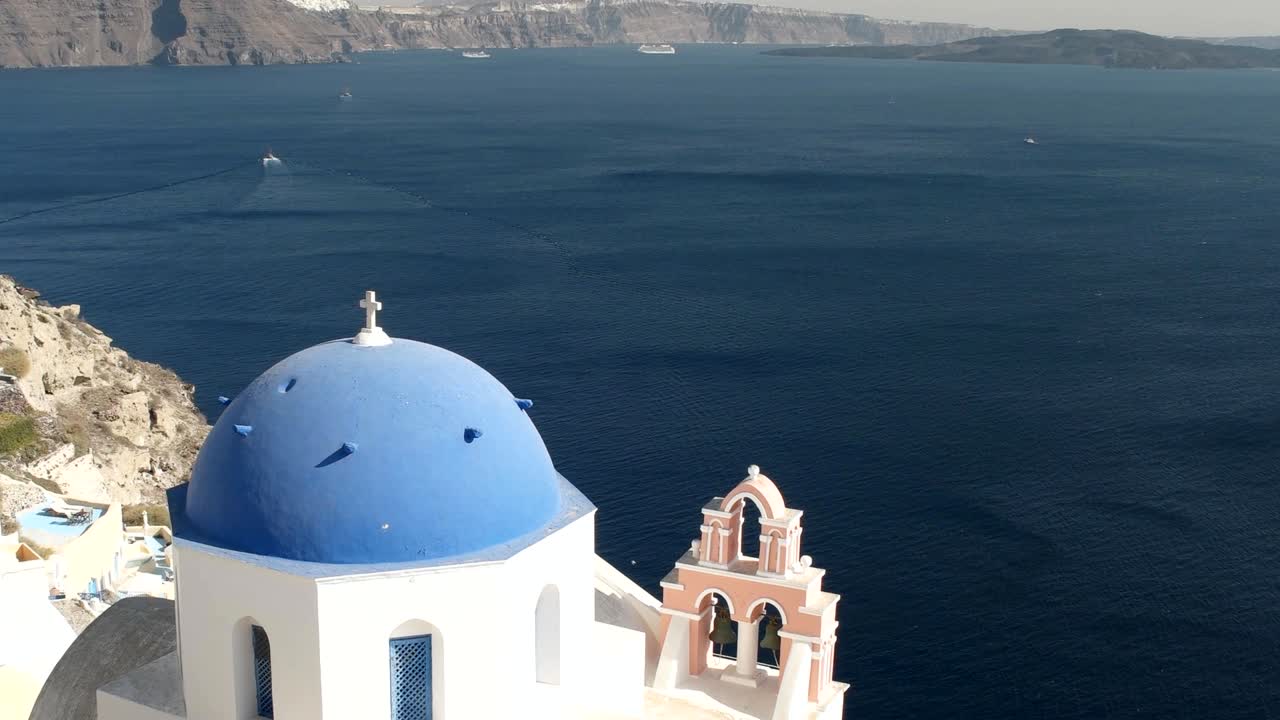 la inclinación de una cúpula azul con fira en la distancia, santorini