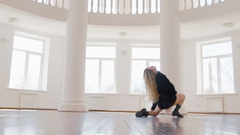 mujer rubia enfocada en jersey suelto de manga larga negra y botas interpretando una danza contemporánea en el estudio 1