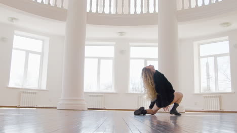 focused blonde woman in black long sleeve loose pullover and boots performing a contemporary dance in the studio 1