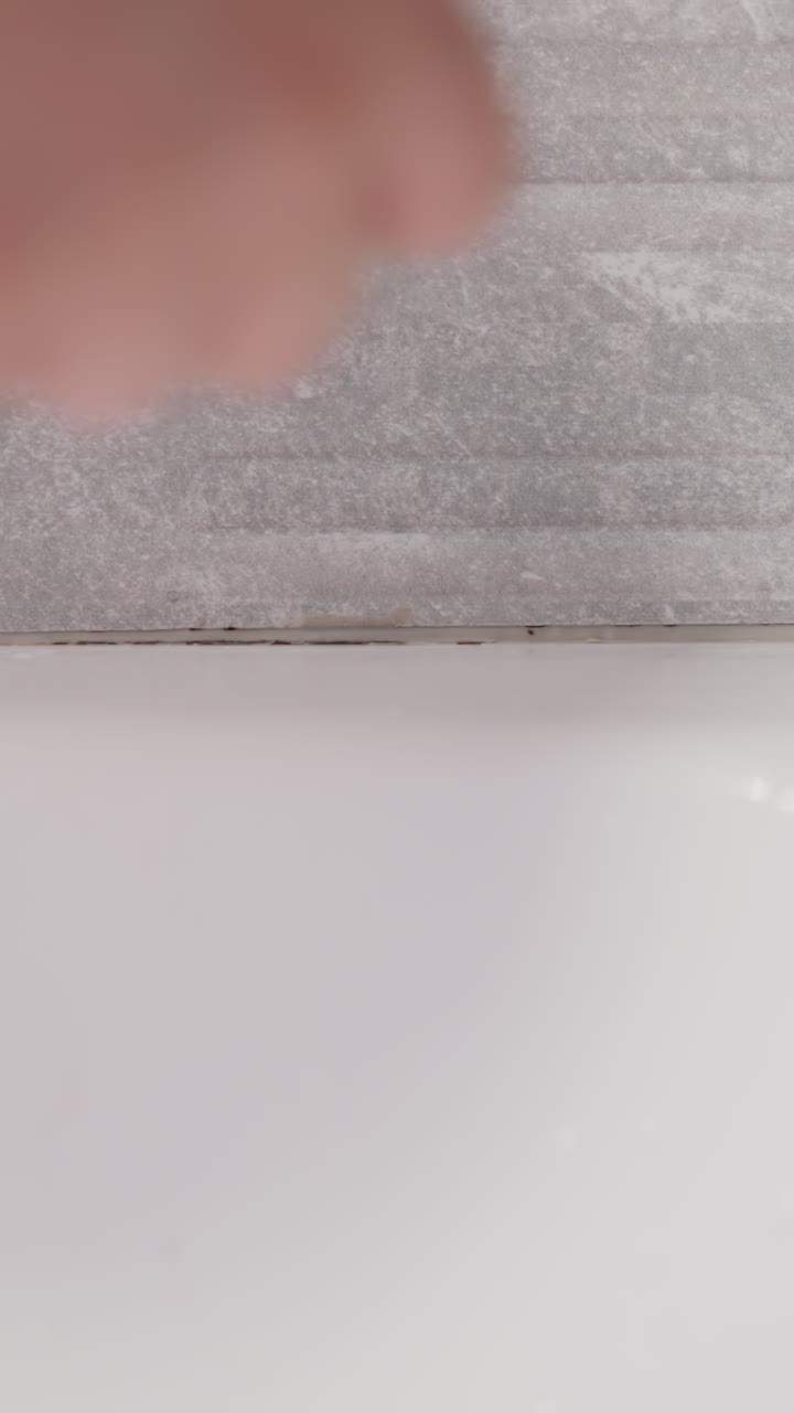 la mano recoge el cabello caído de las paredes del baño. la persona elimina el cabello restante después de tomar una ducha de contraste en la superficie del baño