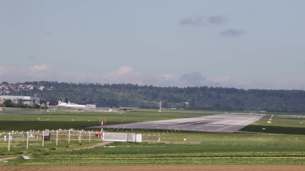 농촌 공항 에 비행기 가 착륙 하고 숲 과 트랙터 가  ⁇  을 가로질러 운전 한다