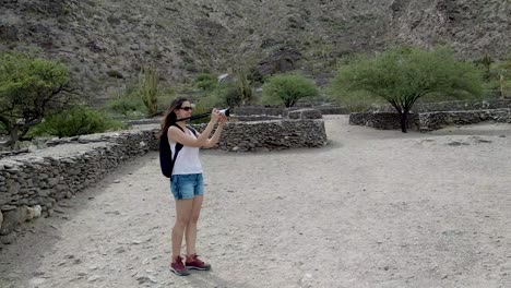 a young, attractive woman shooting video of the quilmes ruins in argentina