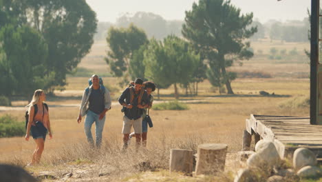 group of friends with backpacks hiking in countryside together