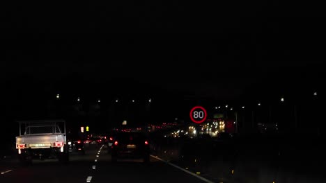 vehicles driving at night with visible speed limit sign