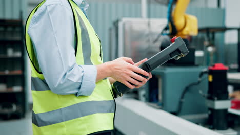 trabajador de la fábrica que opera el panel de control del brazo robótico