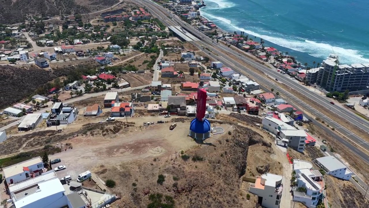 Orbita aerea di drone attorno al Cristo del Sacro Cuore che domina la costa di Rosarito e l'Oceano Pacifico, Messico
