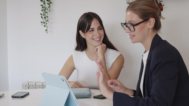 Two business women collaborating on a tablet in an office setting