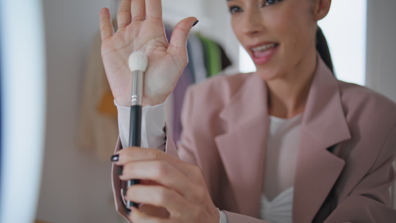una mujer hablando grabando una sala de videoblog de cerca. una mujer sonriente presentando un pincel.