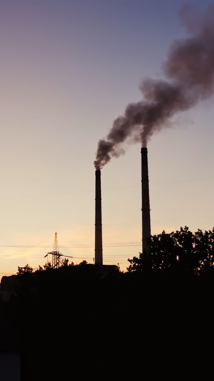 Smoke coming from pipes from factory at darkness. Chemical smoke going into the air from industrial pipes in the city. Vertical video