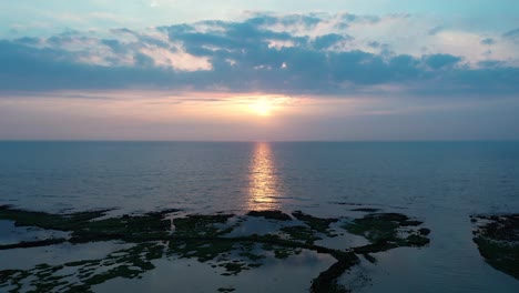 aerial flight towards magnificent sunset with light reflection in tranquil pacific ocean at north coast of taiwan