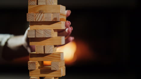 a hand pulls out a wooden block from the tower board games and evening together concept