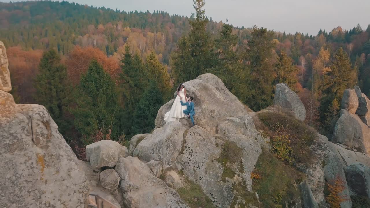 los recién casados están en una ladera alta de la montaña. el novio y la novia.