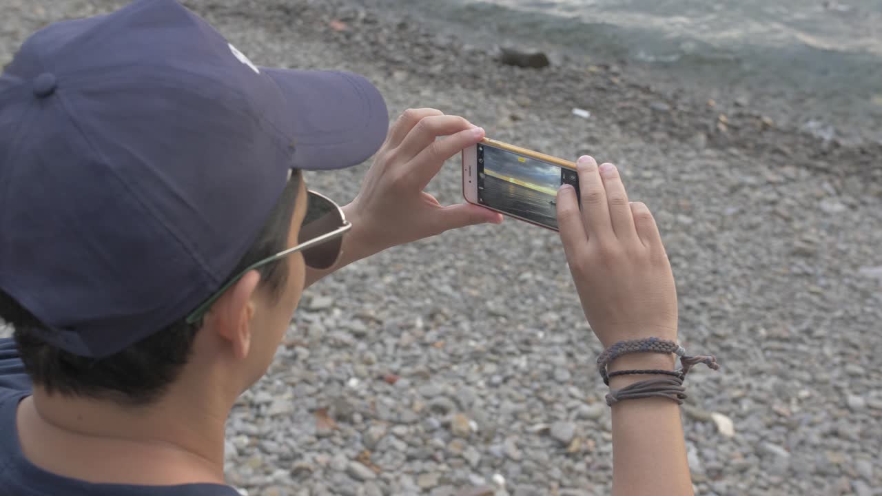 해변에서 일몰 사진을 찍는 남자