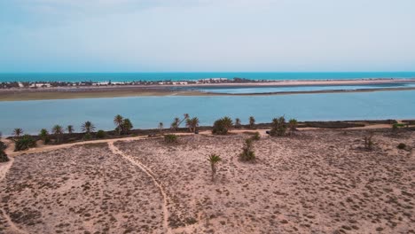 An-aerial-view-of-a-beach,-with-the-ocean-and-sandy-shoreline-visible-in-the-Lagoon-of-Djerba-at-Tunisia-,-ATV-quad-on-A-dirt-pathway-that-crosses-through-the-area