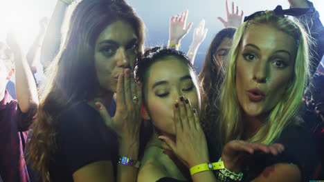 group of women giving flying kiss at a concert 4k