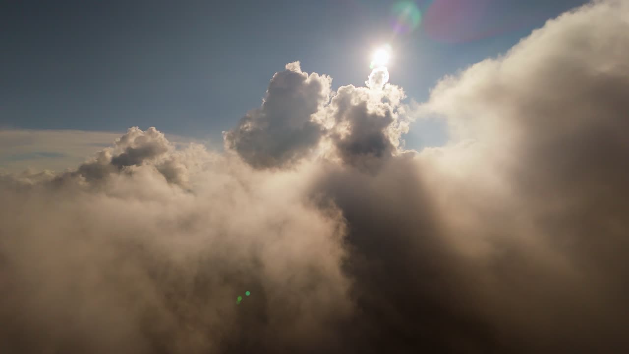 Golden sunlight pierces through dense misty clouds in a cinematic aerial dolly backwards flight