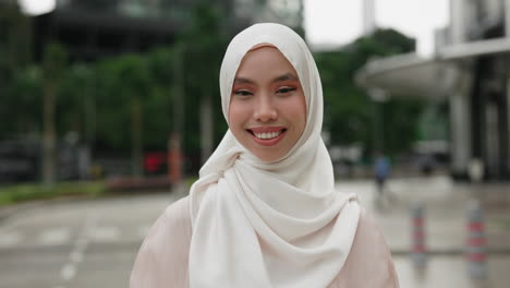 smiling woman wearing hijab in city