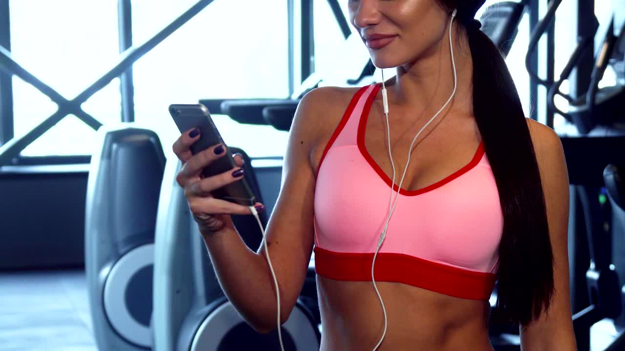 귀여운 소녀는 스포츠 운동 사이에 전화로 무언가를 타이핑합니다.