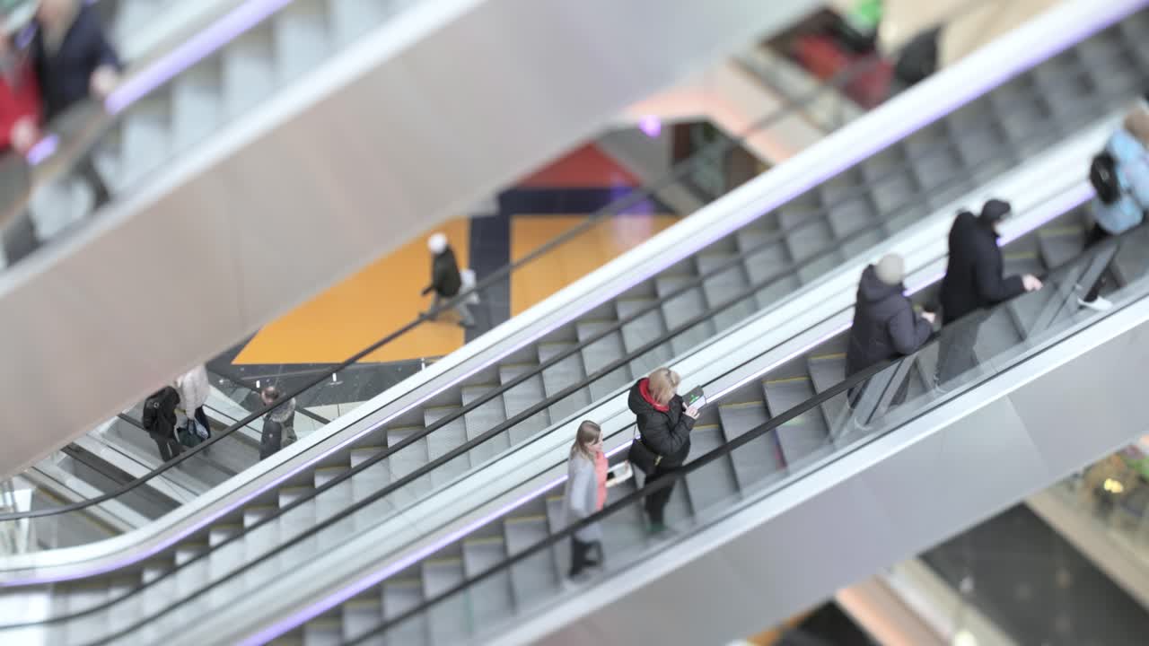 People in motion in escalators at the modern shopping mall. Tilt shift lens shooting with super shallow depth of field.