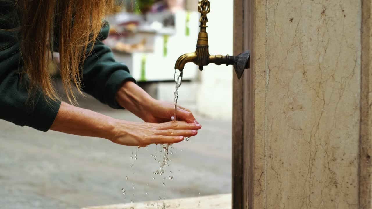 la mujer se lava las manos en la antigua fuente de la calle