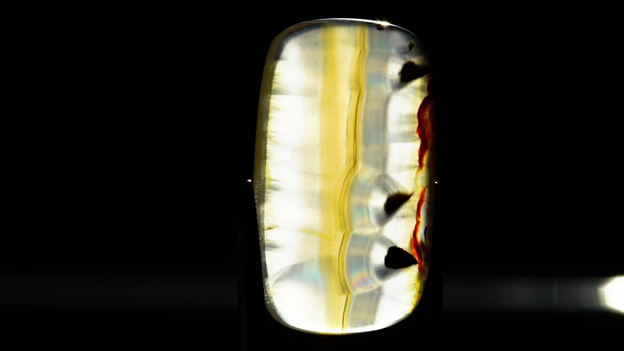 ágata de iris natural en las pinzas sobre el fondo negro