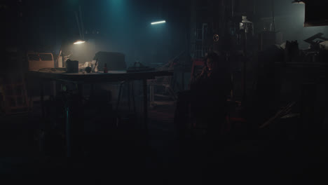 a man in the dark workshop light a cigarette