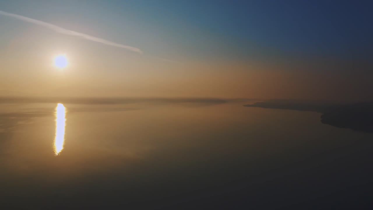 Drone flying above a misty sea coast on golden hour sunset, bird flying over hazy water surface in Lesvos, Greece.