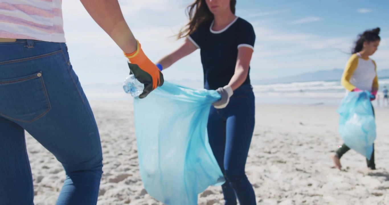 Volunteers pressing bottle from sand and activating floating social metrics during beach cleanup