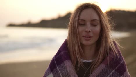 retrato de una niña envuelta en una manta en la playa en otoño