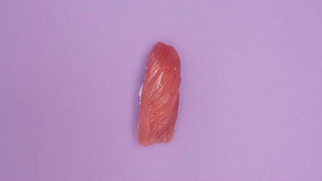 un rollo de sushi girando sobre un fondo violeta