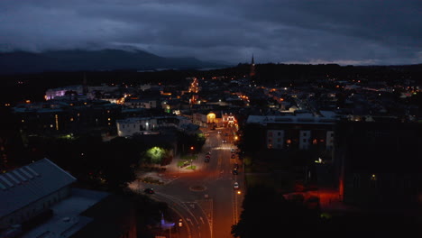 Forwards-fly-above-street-lit-by-orange-street-lights.-Aerial-view-of-town-at-dusk.-Overcast-sky.-Killarney,-Ireland