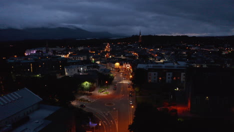 Vorwärtsfliegen-über-Der-Straße,-Die-Von-Orangefarbenen-Straßenlaternen-Beleuchtet-Wird.-Luftaufnahme-Der-Stadt-In-Der-Abenddämmerung.-Bedeckter-Himmel.-Killarney,-Irland