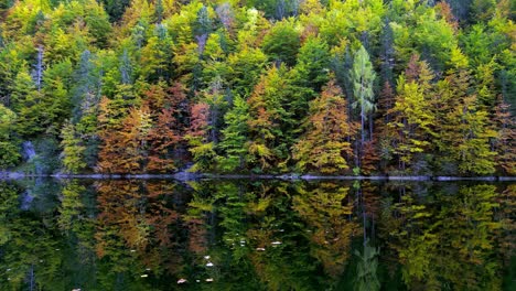 A-lone-kayaker-paddles-across-a-glassy-lake,-dwarfed-by-the-snow-capped-peaks-that-rise-majestically-in-the-distance