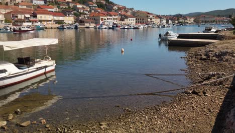 Panning-view-of-a-shallow-harbor-with-its-numerous-small-traditional-boats-docked-along-the-shore-of-Vela-Luka,-Croatia