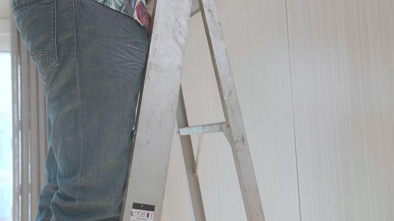 Asian Man On A Ladder Installing Cctv Camera On Wall For Security