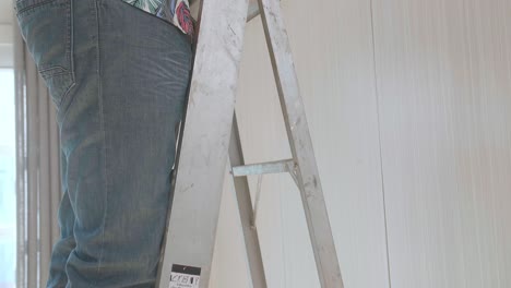 hombre asiático en una escalera instalando una cámara de cctv en la pared para la seguridad
