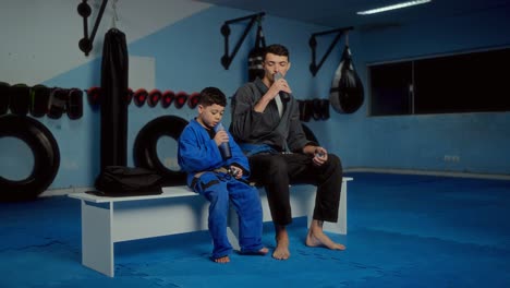jiu-jitsu coach and young student hydrating during a training break