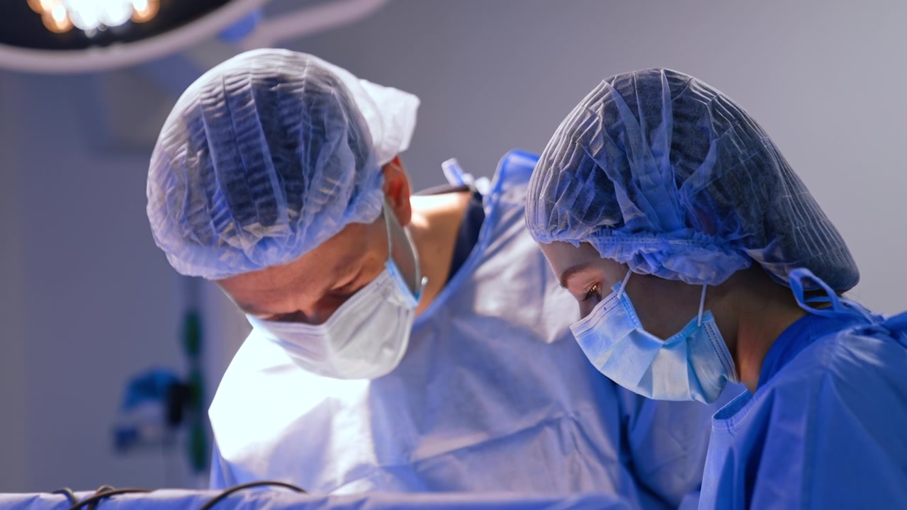Chirurghi e chirurgie, che indossano mascherine, cuffie e camici, collaborano in sala operatoria. Medici concentrati eseguono un intervento neurochirurgico.