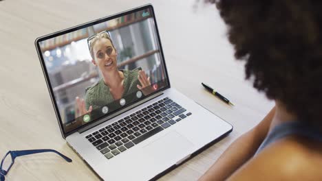 african american businesswoman using laptop for video call with caucasian business colleague